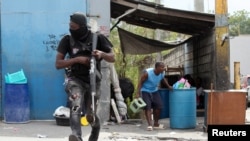 A police officer runs during a clash with gangs as a resident of the Delmas 30 neighborhood flees his home due to gang violence, in Port-au-Prince, Haiti, Feb. 26, 2025. 